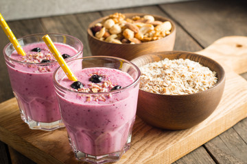 Glasses of berry smoothie with nuts, mint, blueberry, blackberry, raspberry, and yogurt on wooden table. Weight loss and diet concept. 