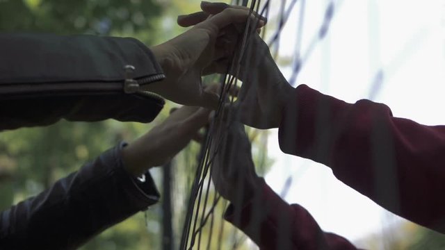 men's hands touching through the net.forbidden love- slow motion