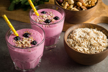 Glasses of berry smoothie with nuts, mint, blueberry, blackberry, raspberry, and yogurt on wooden table. Weight loss and diet concept. 