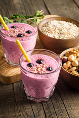 Glasses of berry smoothie with nuts, mint, blueberry, blackberry, raspberry, and yogurt on wooden table. Weight loss and diet concept. 