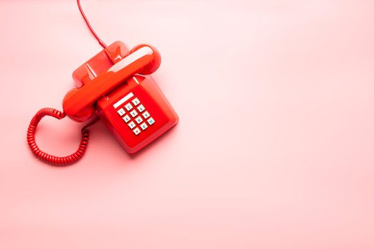 vintage red telephone on pink desk