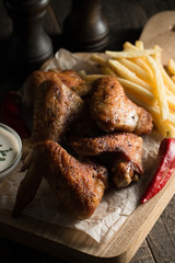 Barbecue grilled chicken wings close up with fries, tomato ketchup sauce and beer on wooden background. Meat food concept. 