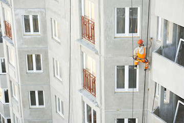 industrial climber. Builder sealing outside facade building seam joints with insulation mastic