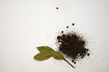 ground black pepper, peas, allspice and Bay leaf on white background