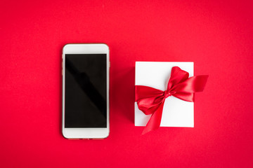 Mobile phone and gift box on red background.