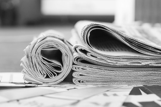 Pile of fresh morning newspapers on pages with headlines and articles at the office. Business news  in daily papers. Folded and stacked journals with selective focus    