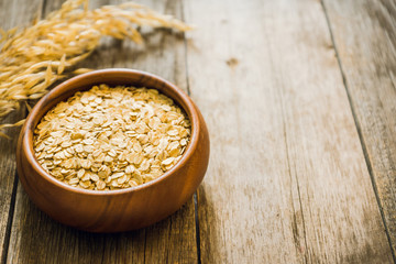 Wooden bowl with uncooked oats on the rustic wooden background. Selective focus. Shallow depth of field.