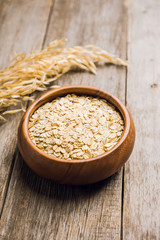 Wooden bowl with uncooked oats on the rustic wooden background. Selective focus. Shallow depth of field.