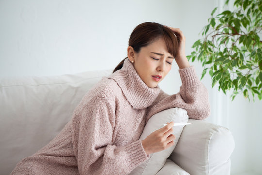 風邪をひいた女性は熱と頭痛に悩まされている