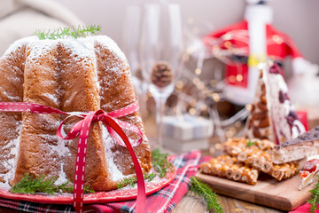 Traditional Italian Christmas fruit cake Panettone Pandoro with festive red ribbon and sweets from...