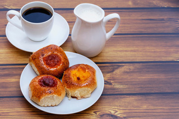 homemade buns with various jams and a cup of coffee with a milk jug close up