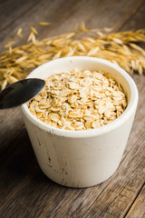 Bowl with uncooked oats on the rustic wooden background. Selective focus. Shallow depth of field. 