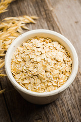 Bowl with uncooked oats on the rustic wooden background. Selective focus. Shallow depth of field. 