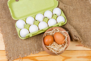 Different chicken eggs in wooden box and paper pulp carton