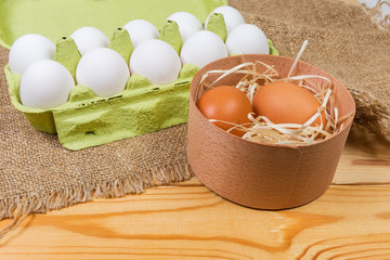 Different chicken eggs in wooden box and paper pulp carton