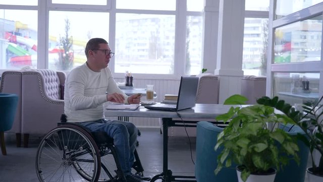internet purchases, successful handicapped into eyeglasses in wheelchair with credit card does online payment using laptop computer during distance education in restaurant