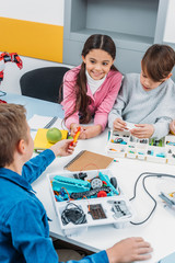 preteen schoolchildren making robot with details in stem education class