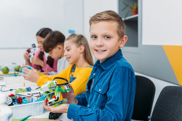 boy showing colorful robot during STEM robotics lesson