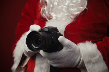 Santa Claus using holding in hands DSLR camera. Christmas and New Year celebration background.
