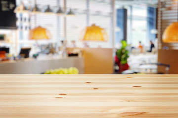 a wooden table with background of blurry modern cafe restaurant interior in a bright day light