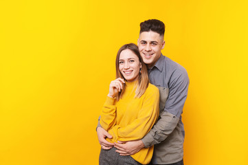 Fototapeta premium Portrait of smiling beautiful young couple standing over yellow background
