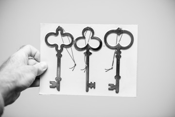 Man holding against white background a set of three vintage ancient keys black and white