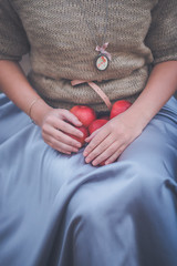 Аpples in the hands of a girl in a knitted sweater and blue skirt. Snow White.