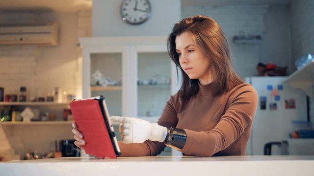 Tablet computer is being operated by a girl with a prosthetic hand