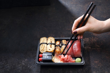 Sushi lunch. Pudełko z sushi .Jedzenie sushi pałeczkami prosto z tacki.