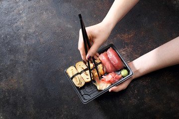 Sushi. Jedzenie na wynos. Jedzenie sushi pałeczkami prosto z tacki.