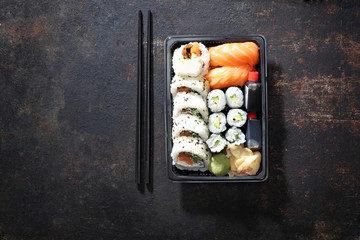 Zestaw sushi. Tacka z kawałkami sushi , imbirem , wasabi i sosem sojowym na ciemnym tle w kompozycji z pałeczkami.