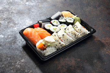 Sushi lunch. Hosomaki, futomaki i nigiri zestaw sushi. Tacka z kawałkami sushi , imbirem , wasabi i sosem sojowym na ciemnym tle.