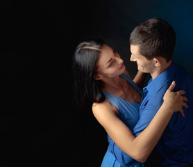 Young beautiful woman in blue dress and man in blue shirt dancing tango.
