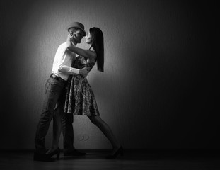 Young beautiful woman in black dress and man in white shirt dancing tango.