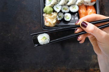 Tacka z kawałkami sushi , imbirem , wasabi i sosem sojowym na ciemnym tle.