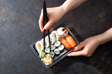 Zestaw sushi na plastikowej tacce. Jedzenie sushi pałeczkami prosto z tacki.