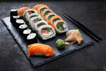 Sushi. . Apetyczne, różnorodne sushi na kamiennym talerzu. Kompozycja na ciemnym tle.
