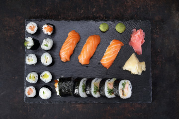 Sushi menu. Apetyczne, różnorodne sushi na kamiennym talerzu. Kompozycja na ciemnym tle.