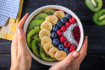 Healthy breakfast with delicious acai smoothie in bowl on dark background