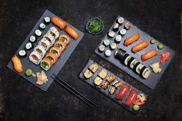Kuchnia japońska, sushi. Apetyczne, różnorodne sushi na kamiennym talerzu. Kompozycja na ciemnym tle. - obrazy, fototapety, plakaty