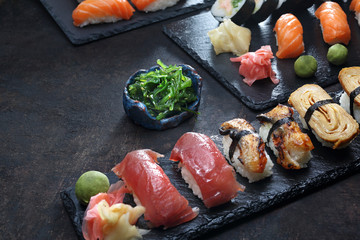 Japońskie sushi. Apetyczne, różnorodne sushi na kamiennym talerzu. Kompozycja na ciemnym tle. - obrazy, fototapety, plakaty