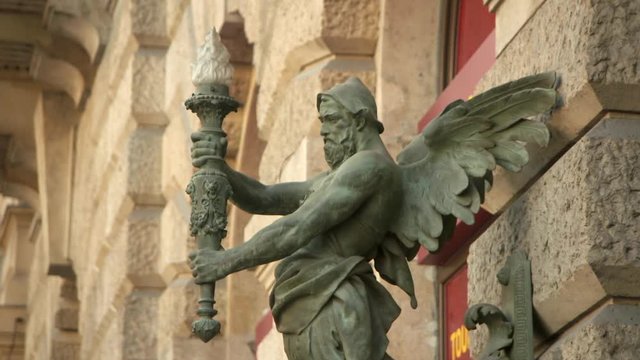 An Intricate Bronze Lighting Sconce in the Shape of a Winged Man on a Wall