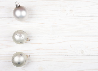 Christmas balls of a silver color in a row on a white wooden background (copy space on the right for your text, top view) as a New Year or Christmas background