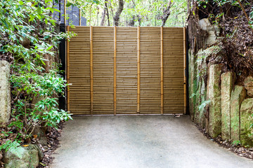 Wooden door swing made of dry bamboo installing on steel frame on Japanese and Chinese  style. That connects the house and the garden. Ideas for Home Design and Decoration.