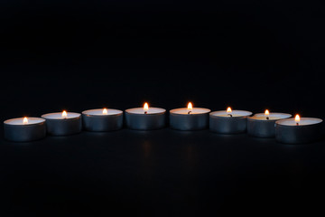 seven candles on a black background