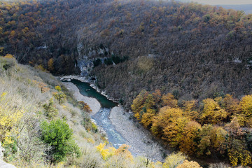 River bends through a colorful autumn forest surrounded by high mountains