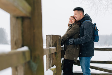 Winter portrait of young beautiful happy smiling couple outdoors. Christmas and winter holidays. Man and woman in snowy park