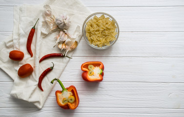 Ingredients. Red peppers, chilli peppers, garlic and tomatoes on a white fabric background. White wooden background. Top view. Copy space. 