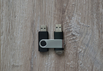 Two flash drives together on brown wooden background. Top view