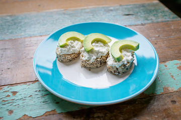sandwich: healthy bread with seeds with cream cheese and avocado on the plate on the table
